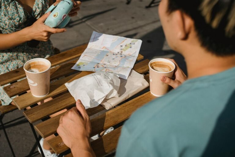 A couple with coffee and a map planning their travel adventure at an outdoor cafe.