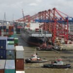 a tug boat in the water next to a large cargo ship