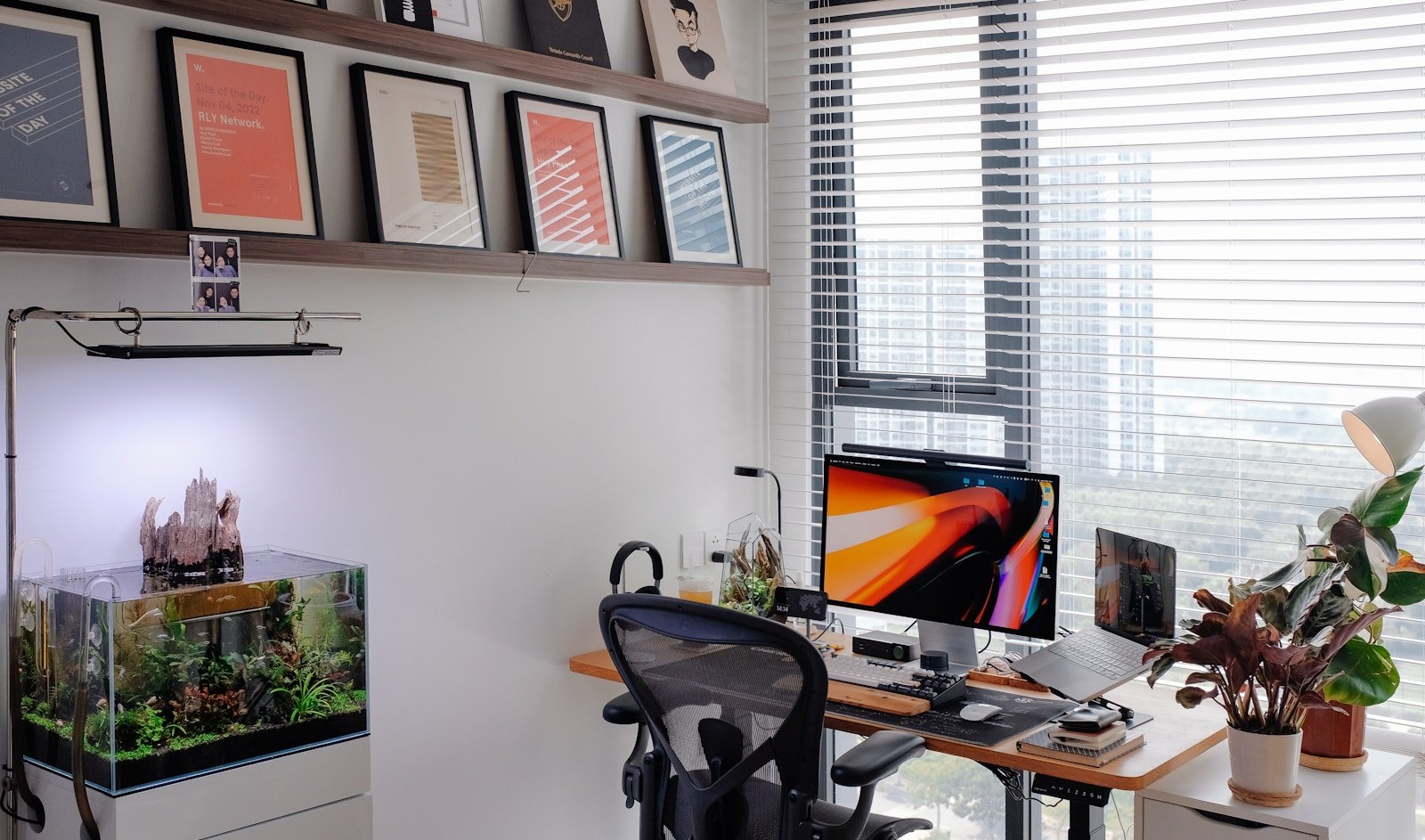 A modern home office with framed art and an aquarium.